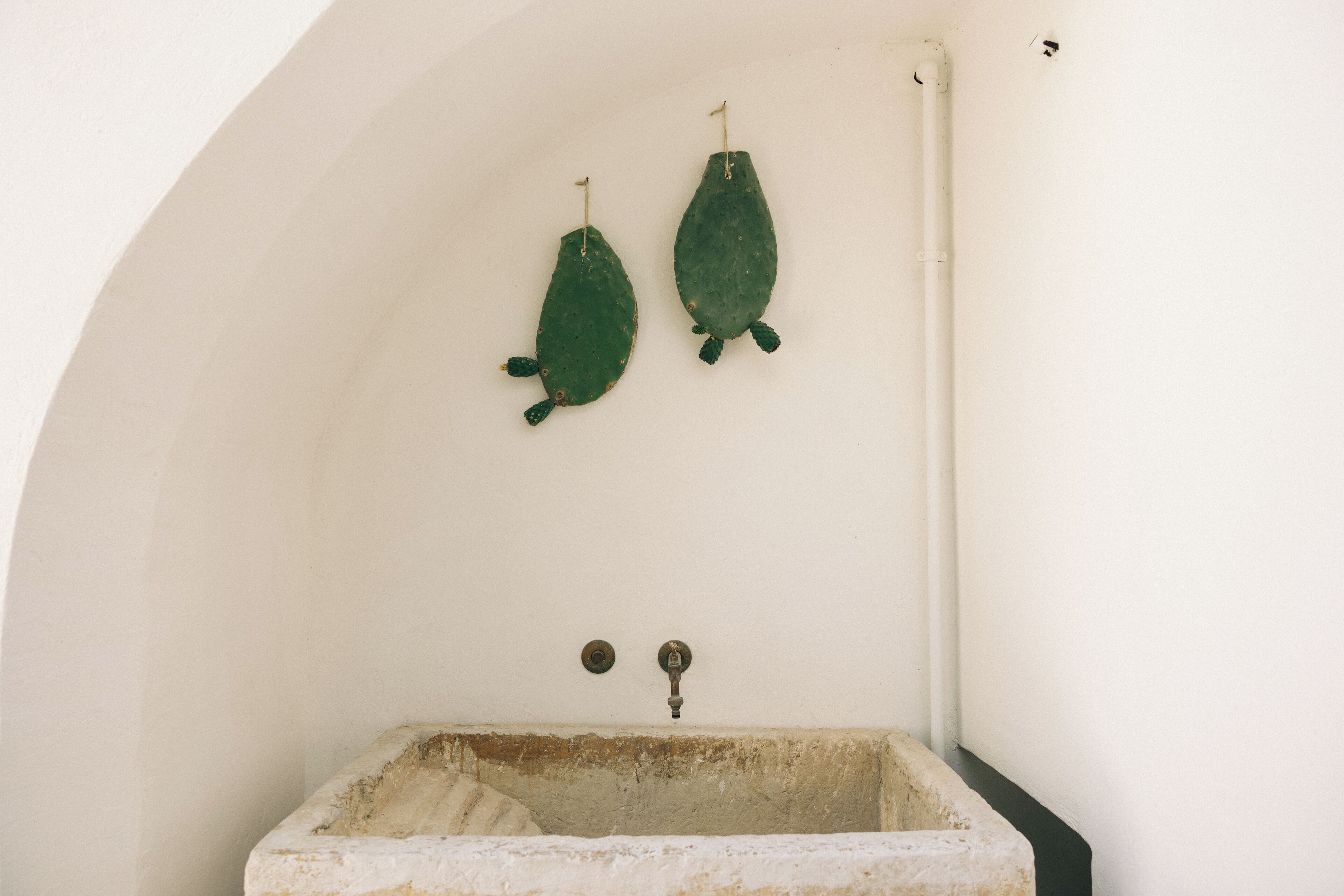 Ein kleines, rustikales Badezimmer mit einer weißen, gewölbten Decke und einem einzelnen, alten Waschbecken.