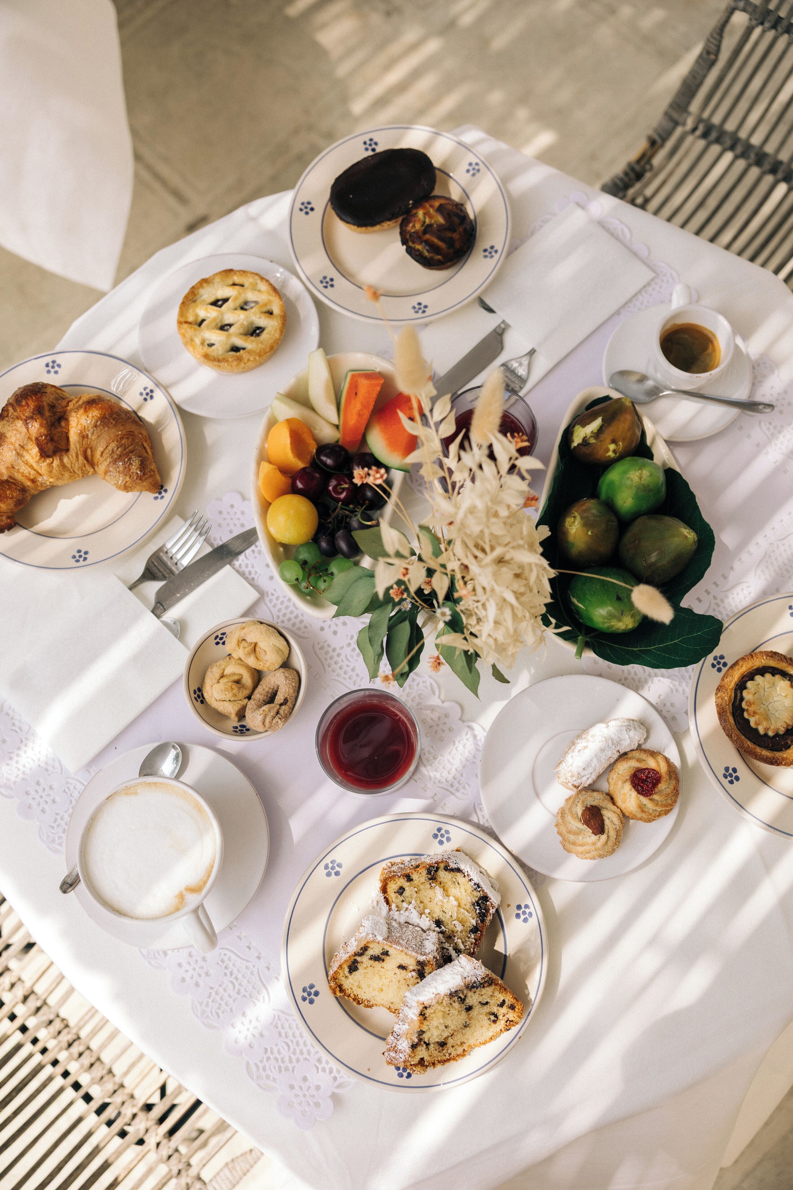 A table set with various pastries, fruits, and a coffee cup, suggesting a breakfast or snack setting.