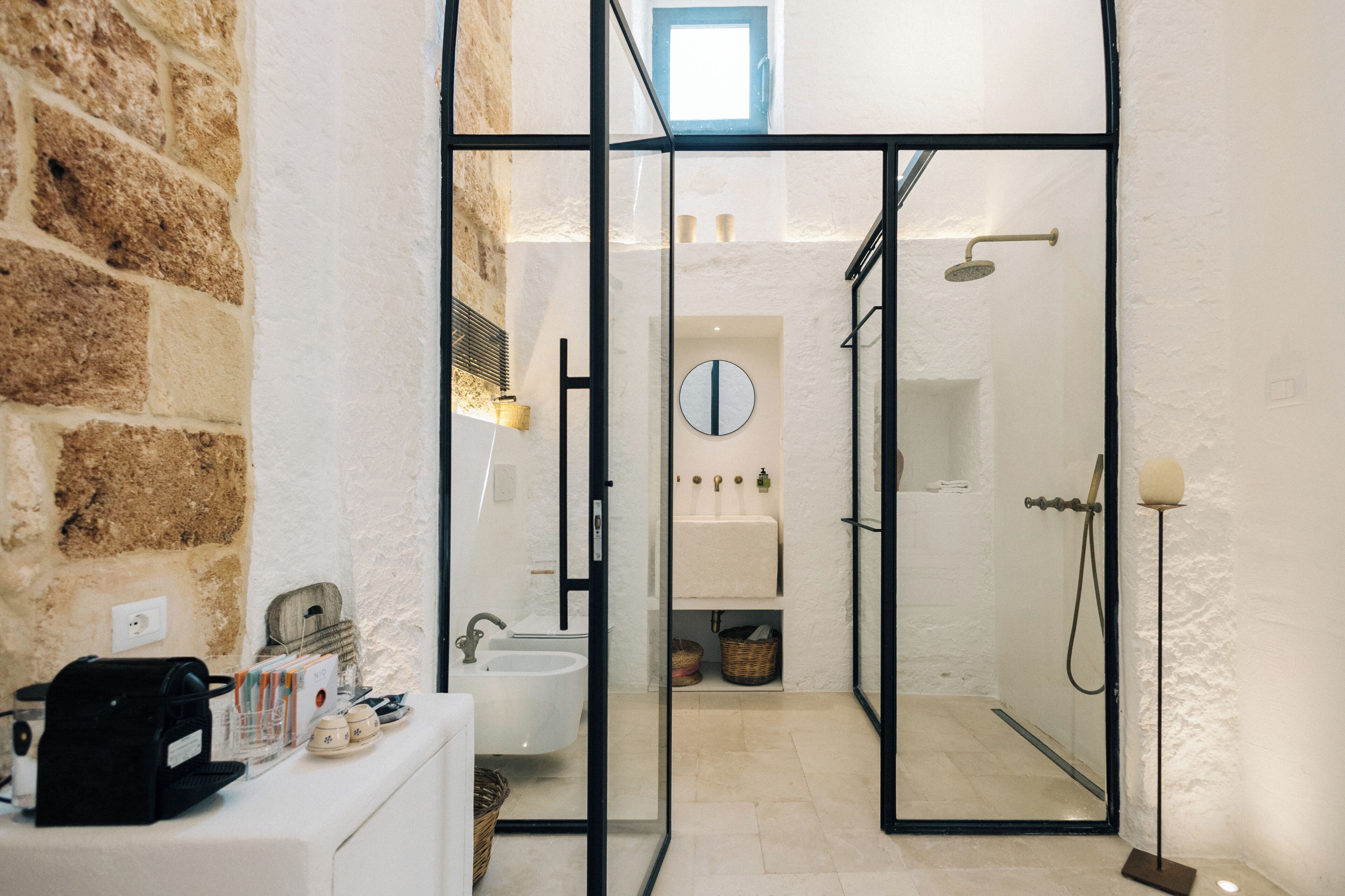 Une salle de bain avec une porte en verre, un lavabo, un miroir et une douche.