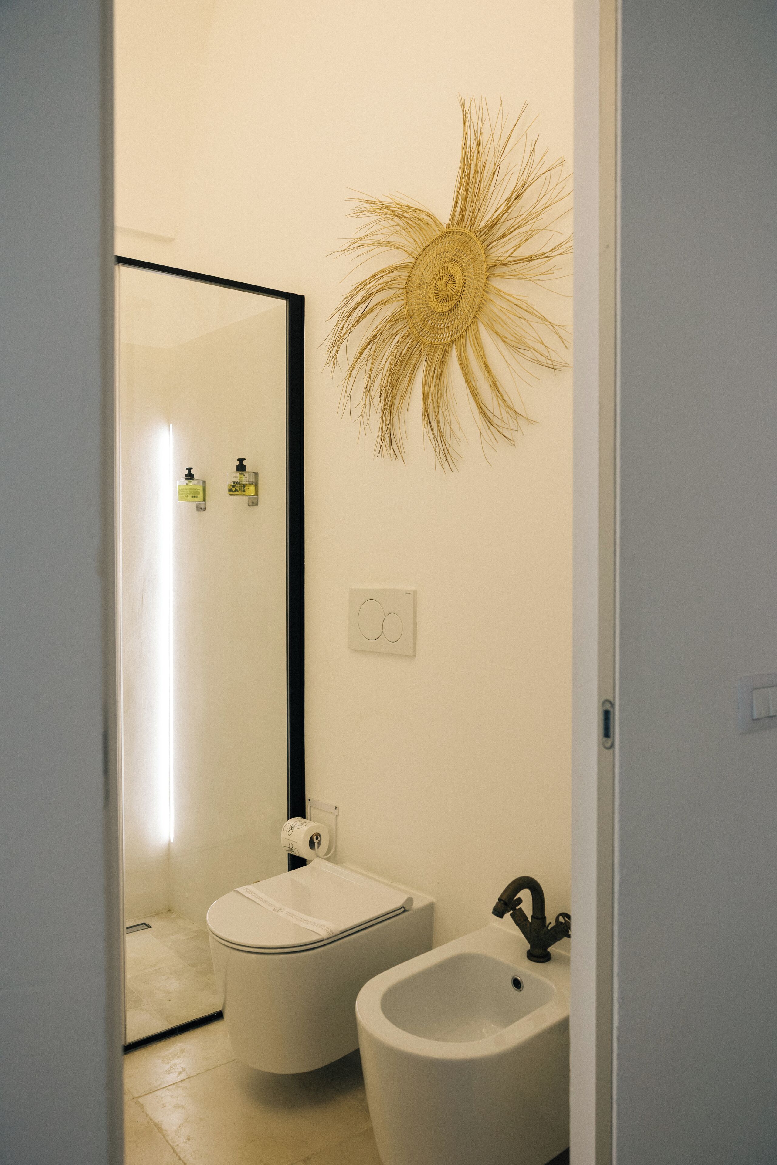 Ein Badezimmer mit Toilette, Bidet und einer dekorativen Wandgestaltung.