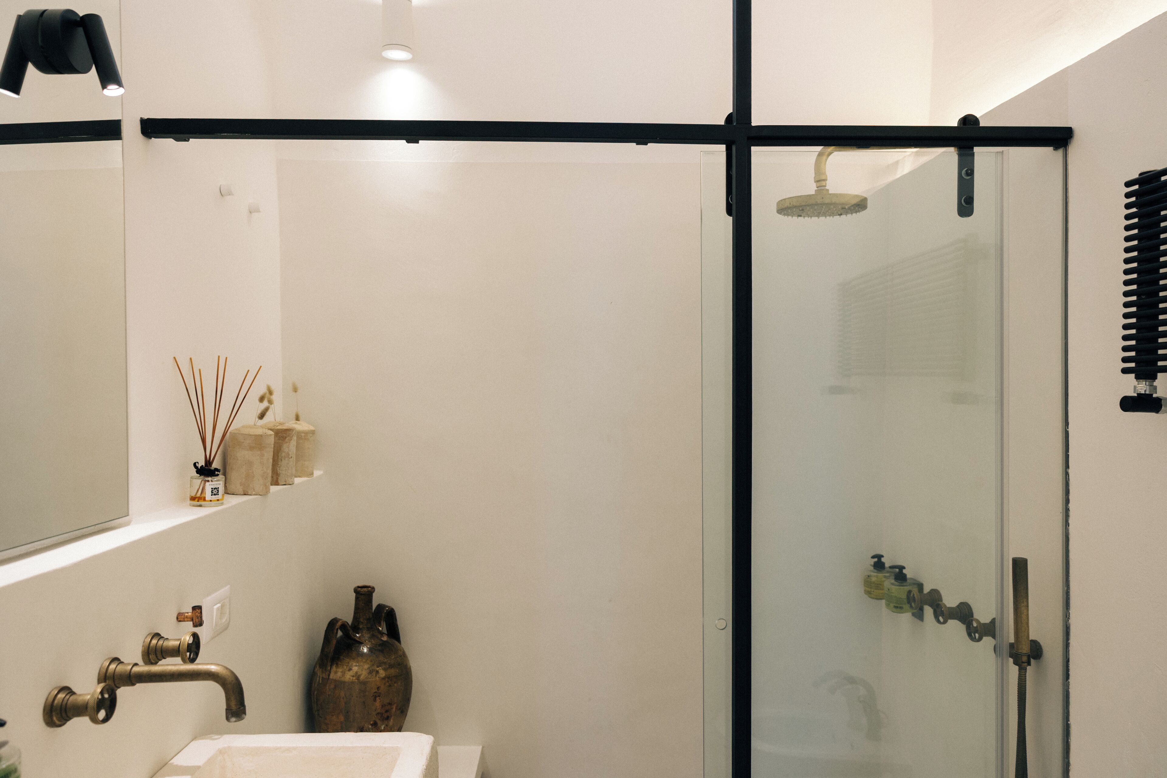 Un bagno moderno con cabina doccia in vetro, un lavandino bianco e un rubinetto in stile vintage.