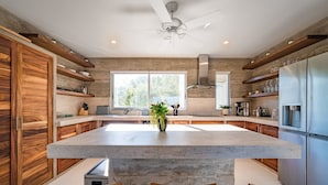 A modern kitchen with a large island, wooden cabinets, and built-in appliances. - Surf-Friendly Penthouse – Ocean Views, 3-Min Walk to the Beach (Bahias de Huatulco)