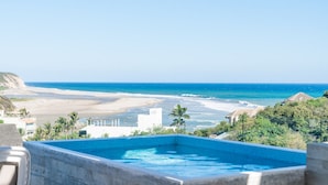 A pool with a view of the beach and ocean. - Surf-Friendly Penthouse – Ocean Views, 3-Min Walk to the Beach (Bahias de Huatulco)