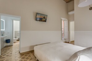 Een slaapkamer met een bed, een schilderij aan de muur en een badkamer zichtbaar door een open deur.