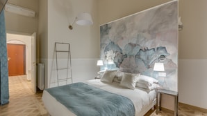 A bedroom with a large bed, a headboard with a marble-like design, two bedside lamps, and a ladder against the wall. - Selected & Private apARTment. Double check cleaning mode. Smart customer service (Roma)