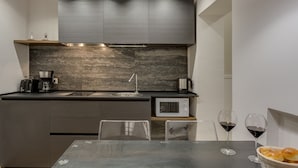 A modern kitchen with a dark countertop, stainless steel appliances, and a dining area with a table and chairs. - Selected & Private apARTment. Double check cleaning mode. Smart customer service (Roma)