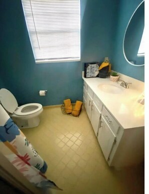 A bathroom with a toilet, sink, and window.