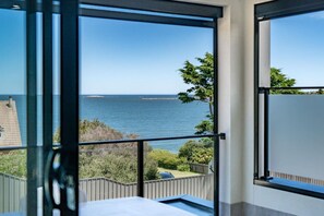 Un balcon avec vue sur la mer et une île lointaine.