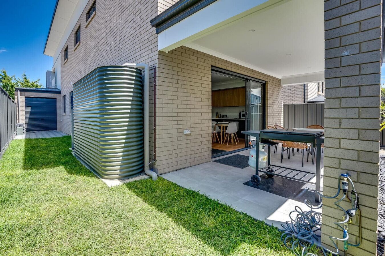 Une maison moderne dotée d’un patio couvert, d’une grande citerne d’eau et d’un espace cuisine ouvert.