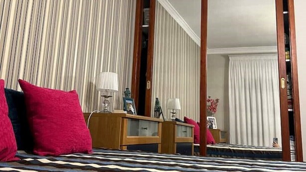 A hotel room with a bed, a wooden dresser, a mirror, and a view of the hallway. - COCONUT HOUSE. (Puerto del Rosario)
