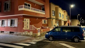 A multi-story building with balconies, a blue van parked in front, and a pedestrian crossing. - COCONUT HOUSE. (Puerto del Rosario)