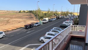 A balcony with a view of a parking lot and a road. - COCONUT HOUSE. (Puerto del Rosario)