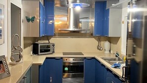 A compact kitchen with blue cabinets, a microwave, an oven, and a stainless steel refrigerator. - COCONUT HOUSE. (Puerto del Rosario)