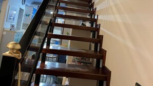 A wooden staircase with a black handrail leading to a landing. - COCONUT HOUSE. (Puerto del Rosario)