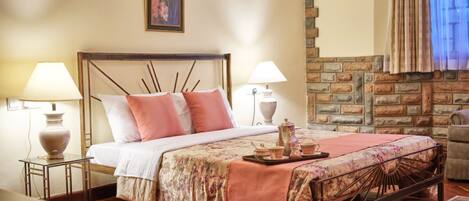 A neatly arranged bedroom with a bed, bedside lamps, a small table, and a decorative tray.