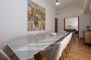 Un espace repas moderne avec une longue table, des chaises confortables et un grand tableau accroché au mur.