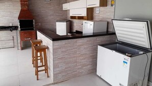 Una cocina con horno de ladrillo, armarios blancos, un refrigerador y taburetes de madera.