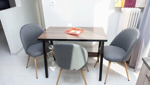 A dining area with a wooden table and two grey upholstered chairs with wooden legs. - Gorgeous apt in Faliro with view (Palaio Faliro)