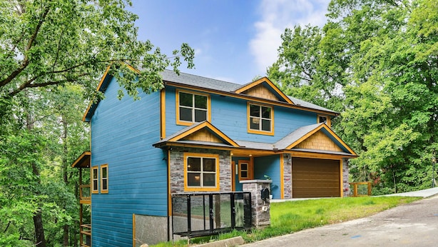 A two-story house with a stone facade, a garage, and a covered porch.