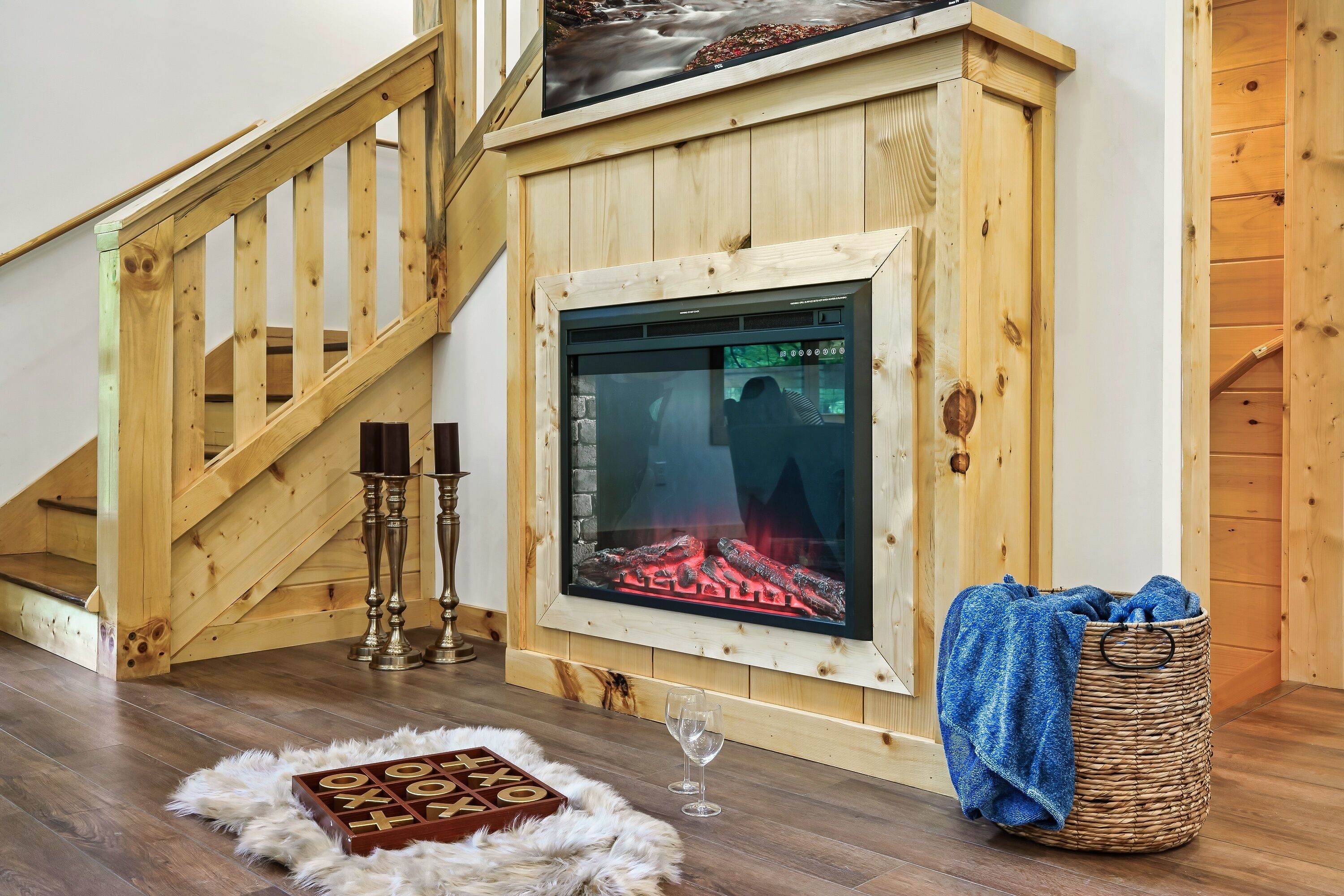 Una habitación acogedora con chimenea, escalera de madera y una cesta con toalla.