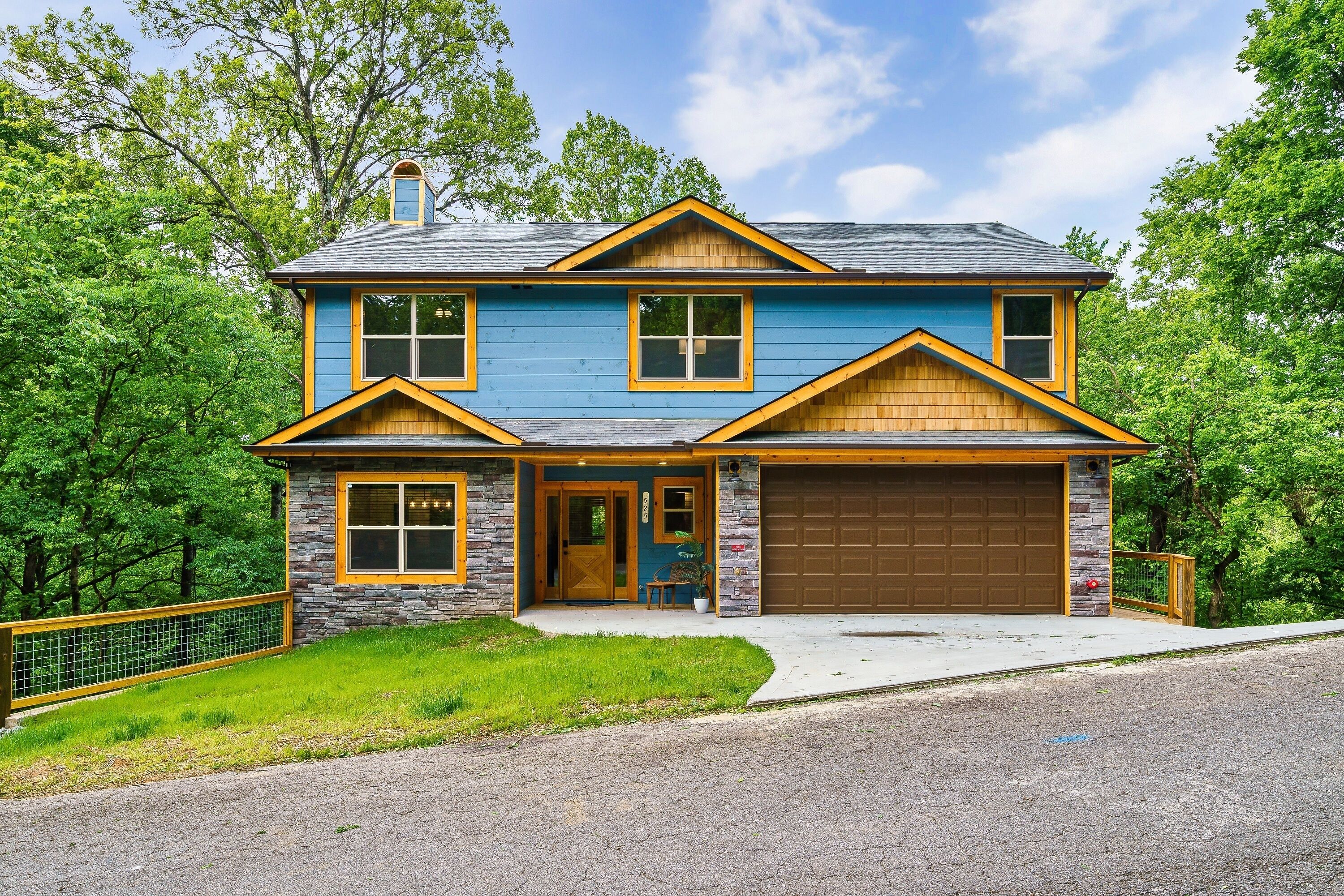 A two-story house with a stone facade, a blue exterior, and a brown garage door.