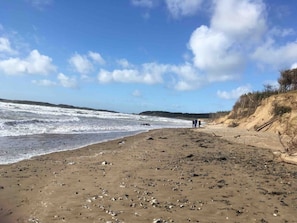 A beach with waves, a sandy shore, and a few people walking.