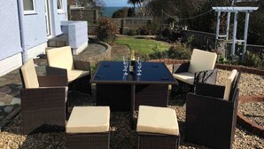 An outdoor patio with wicker furniture, a table, and a view of the sea. - Benllech Sea View bungalow, Dog Friendly sleeps 6 (Benllech)