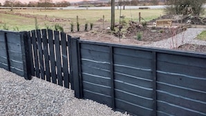 A fenced garden with a wooden bench, a stone wall, and a view of a field and distant hills. - A real gem of a cottage. (Alyth, near Blairgowrie)