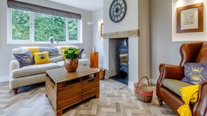 Un salon chaleureux avec une cheminée, un canapé, une table basse et un fauteuil en cuir.
