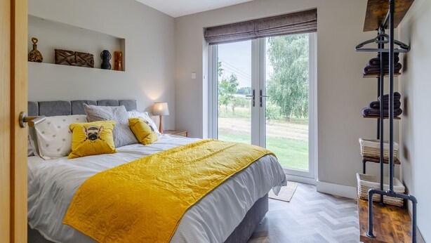 Une chambre à coucher comprenant un lit, une fenêtre, une table de chevet et une étagère fixée au mur.