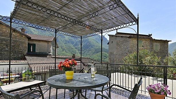 A balcony with a round metal table, two chairs, a yellow vase with flowers, and a bottle of white wine. - Medieval house in the countryside; 20 km from Alassio' beach (Vesallo)
