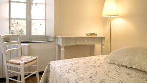 A bedroom with a bed, a bedside table, a lamp, a chair, and a window. - Medieval house in the countryside; 20 km from Alassio' beach (Vesallo)