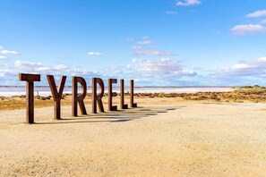 Large metal letters spelling "TYRRELL" on a beach.