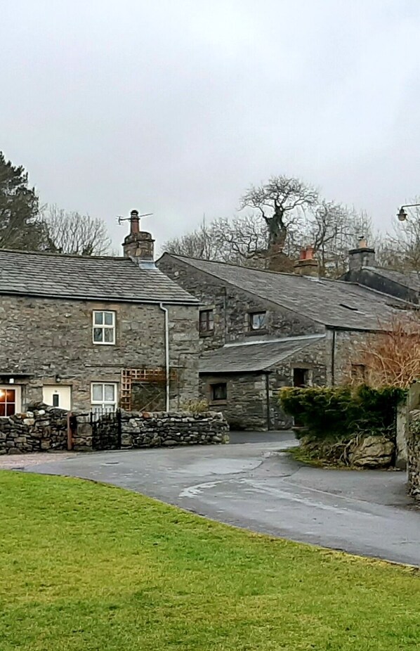 A stone building with a paved driveway and a grassy area in front.