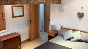 Un dormitorio con una cama grande, cabecera de madera, una mesita de noche, un tocador y una decoración de corazón en la pared.