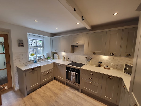 A modern kitchen with grey cabinets, a black stove, and a window with a view of the outside.