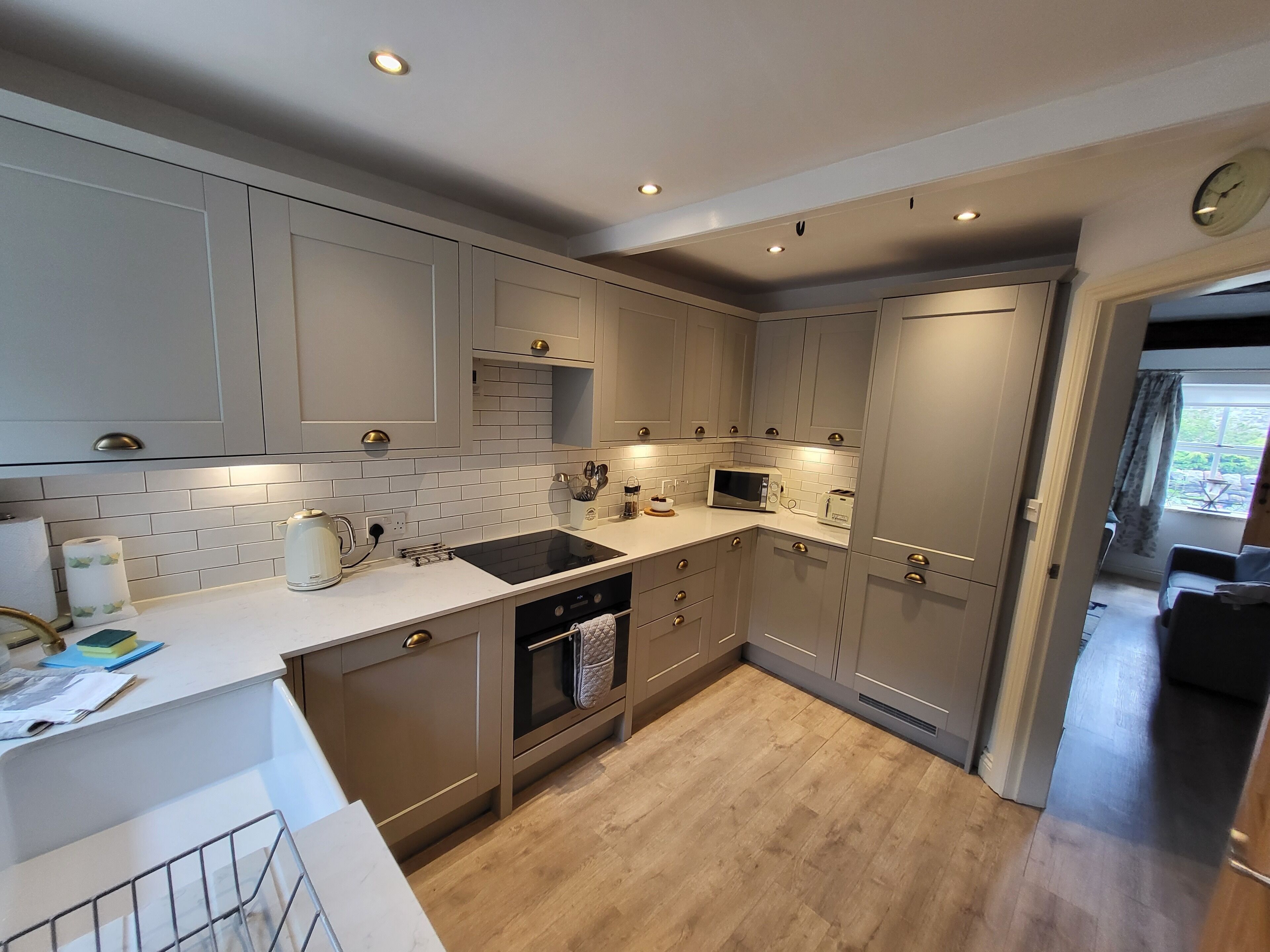 A modern kitchen with grey cabinets, a white countertop, and a built-in oven.