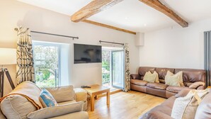 A living room with a wooden ceiling, a sofa set, a TV, and a window with curtains. - 3 bedroom accommodation in Ingleton (Ingleton)