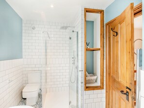 A bathroom with white tiled walls, a glass shower enclosure, a wooden door, and a toilet. - 3 bedroom accommodation in Ingleton (Ingleton)
