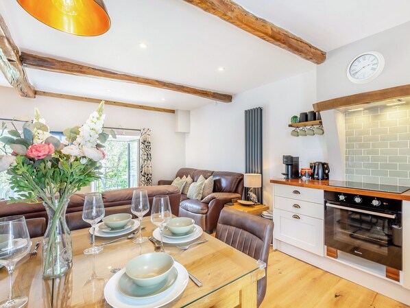 A modern kitchen with a built-in oven and a dining area with a wooden table set for a meal. - 3 bedroom accommodation in Ingleton (Ingleton)
