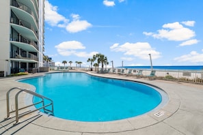 A swimming pool with a curved edge, a metal handrail, and a view of the ocean.