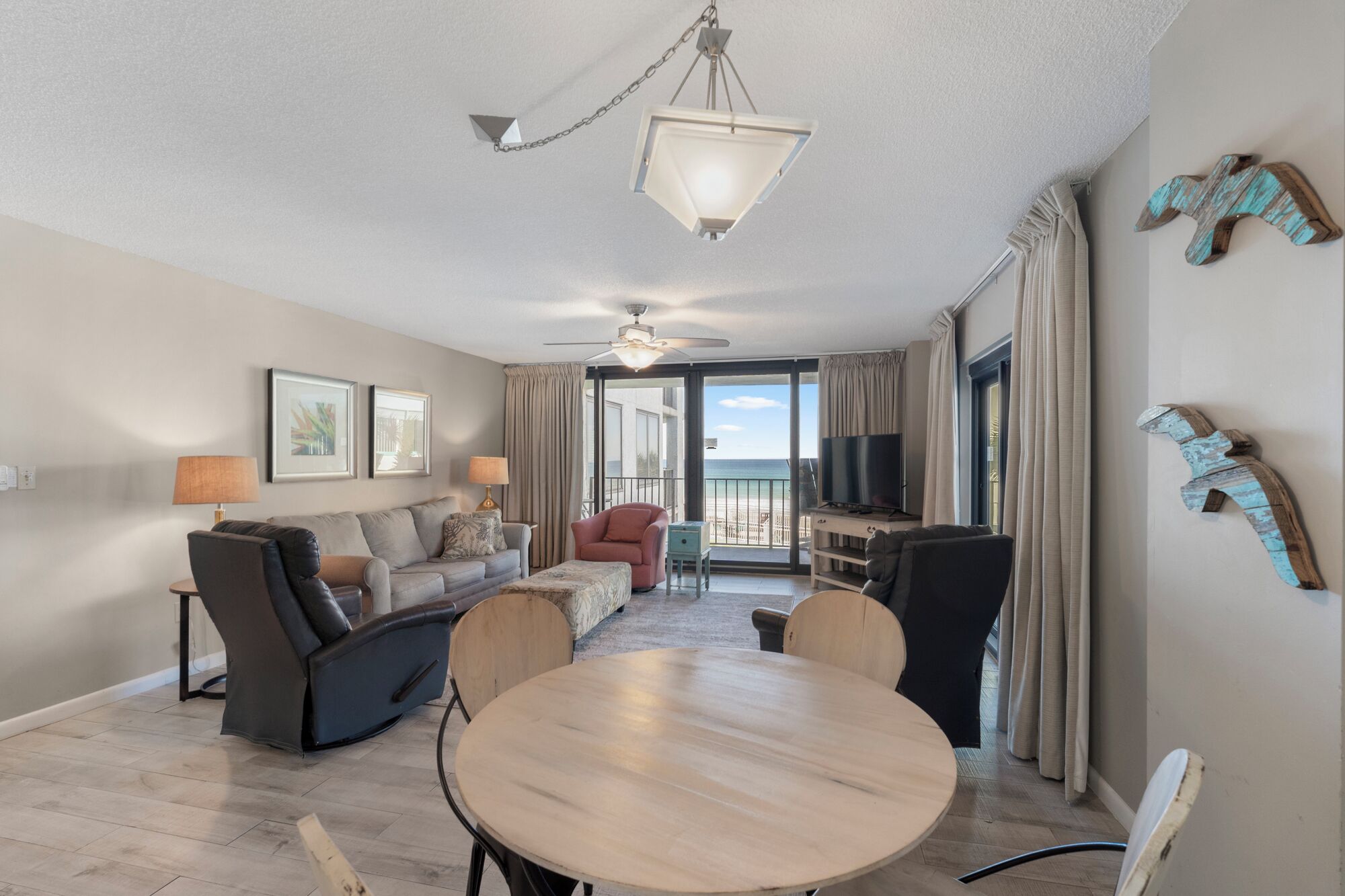 A spacious living room with a round wooden table, a sofa, a chair, and a TV stand.
