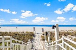 A beach path leading to the ocean with white railings and informational signs.