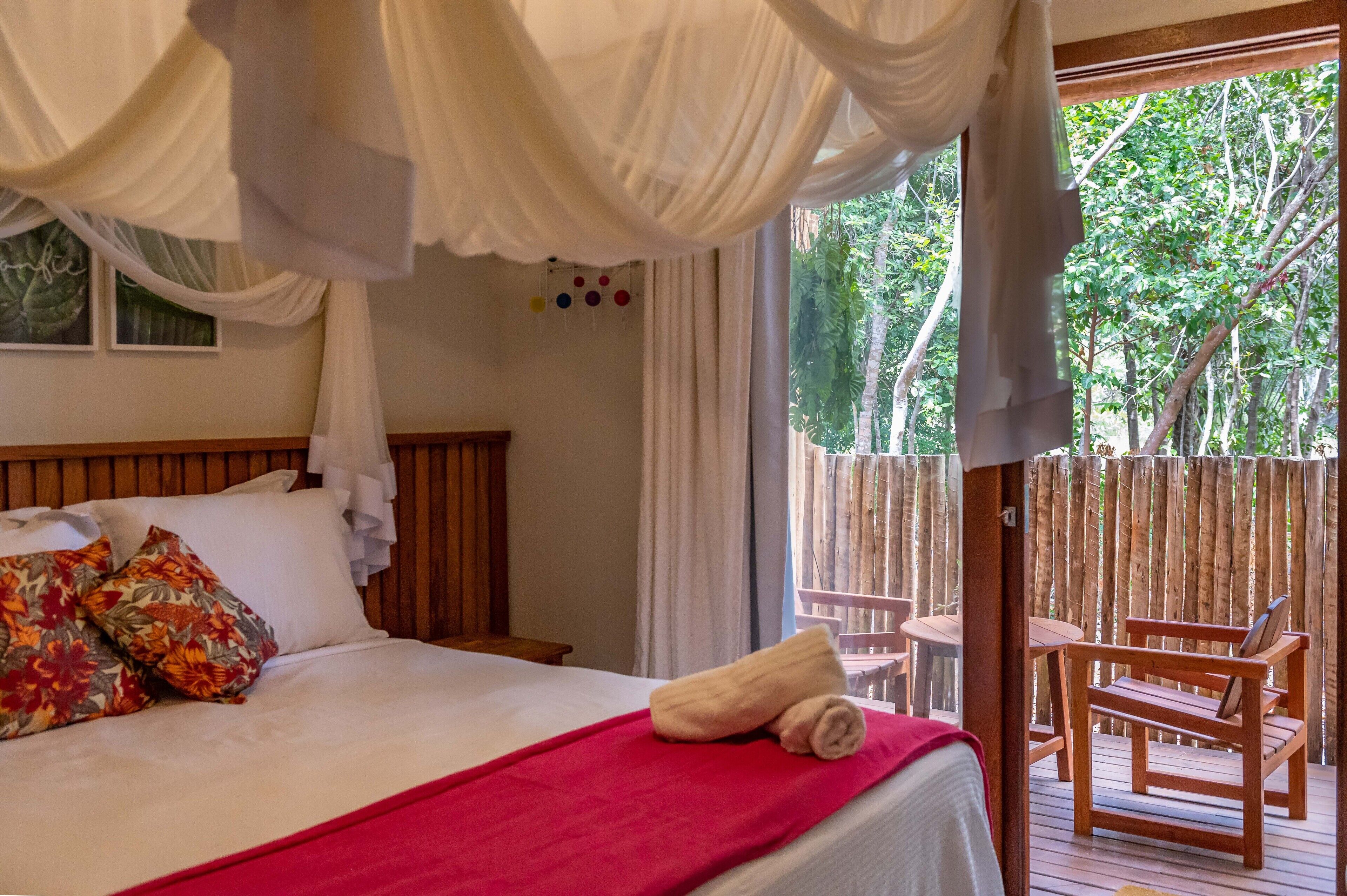 Ein Schlafzimmer mit Baldachinbett, Holzfußteil und einem Balkon mit Holzmöbeln.