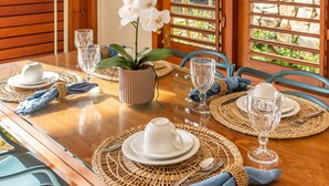 Mesa de comedor dispuesta con platos, vasos y una orquídea en maceta.