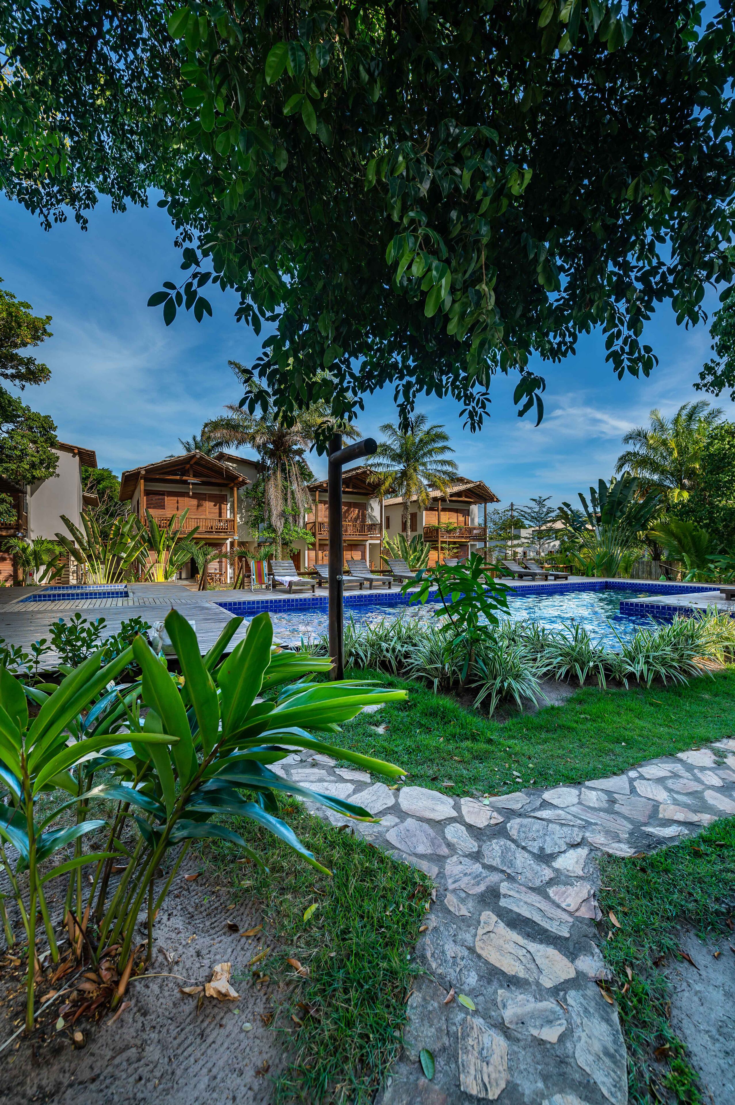 Ein Resort mit Schwimmbad, Holzhütten und üppiger Vegetation.