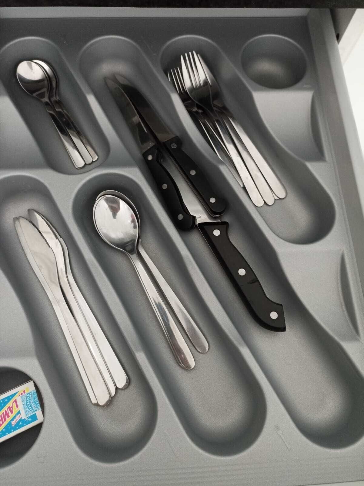 A drawer containing neatly arranged cutlery including a spoon, knife, fork, and a pair of chopsticks.