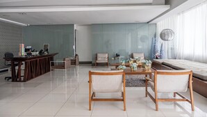 Una sala de estar moderna con un separador de vidrio, una mesa de comedor de madera con sillas, un sofá y un globo decorativo.