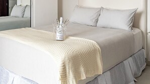 Un dormitorio ordenado con una cama grande, una mesita de noche y una lámpara colgante.
