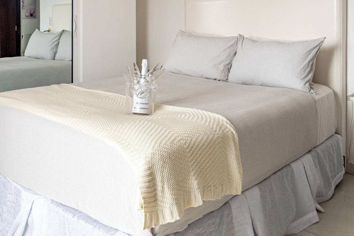A neatly arranged bedroom with a large bed, a bedside table, and a hanging light fixture.